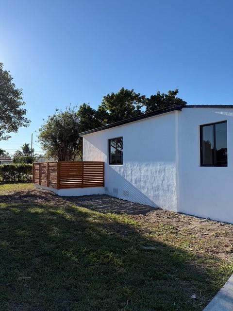 The exterior of a white house features a wooden privacy fence and two windows — 1800 SW 75th Ave Rd, Miami FL 33155, MIAMI, FL
