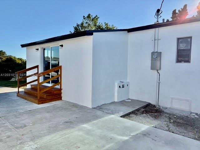 The exterior of a white house features a wooden staircase leading to a sliding glass door — 1800 SW 75th Ave Rd, Miami FL 33155, MIAMI, FL