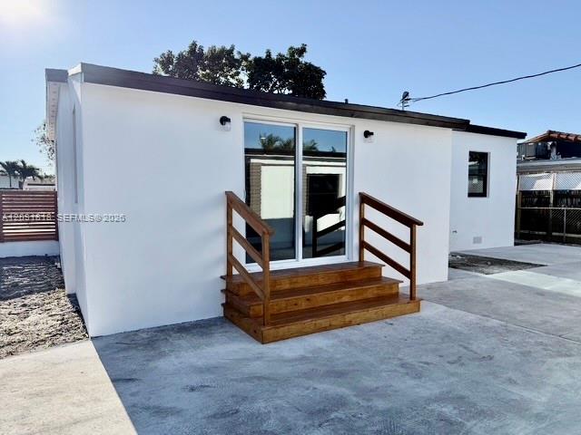 The exterior of a white house features a wooden staircase leading to sliding glass doors — 1800 SW 75th Ave Rd, Miami FL 33155, MIAMI, FL