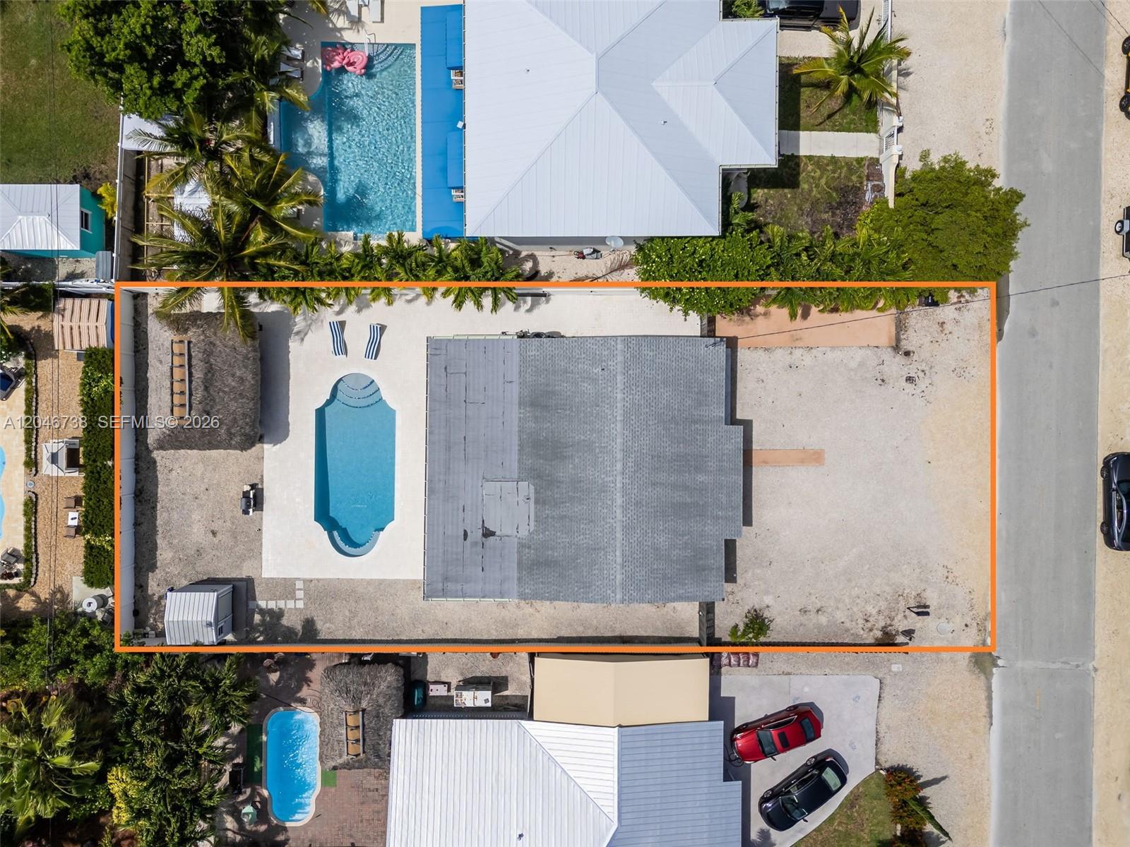 An aerial view shows a house with a pool, a tiki hut, and a gravel yard — 16 Fishermans Trl, Key Largo FL 33037, KEY LARGO, FL