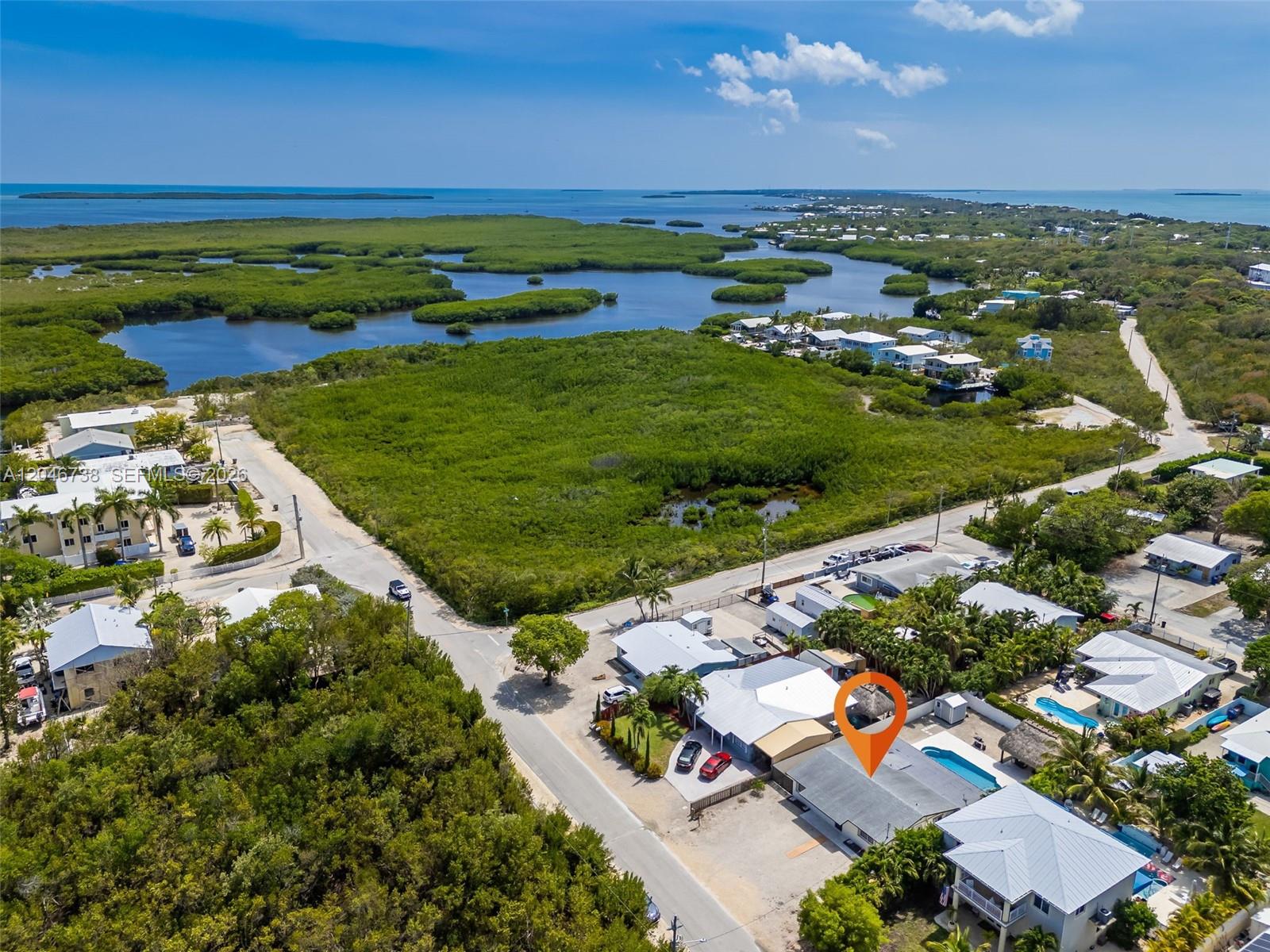 An aerial view shows a residential property with a swimming pool and a tiki hut — 16 Fishermans Trl, Key Largo FL 33037, KEY LARGO, FL