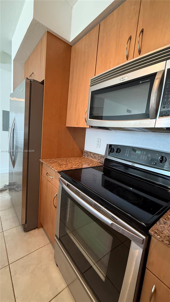 A kitchen features wood cabinets, stainless steel appliances, and granite countertops — 1830 Radius Dr # 915, Hollywood FL 33020, HOLLYWOOD, FL