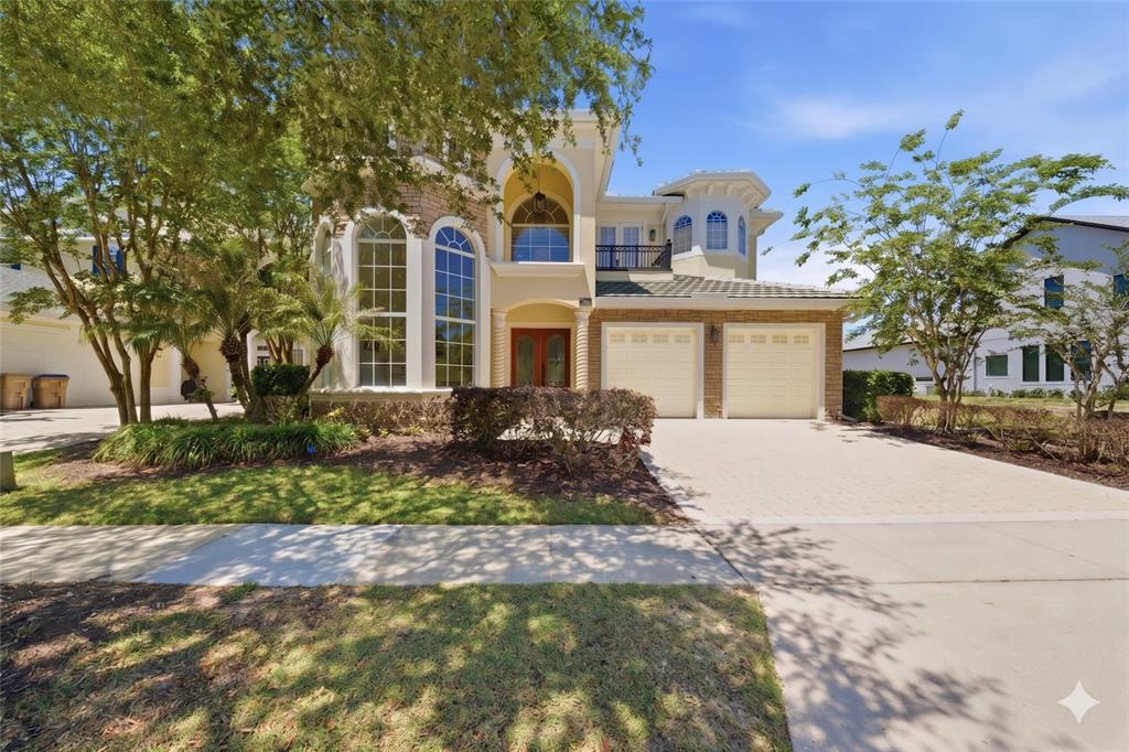A two-story house with a beige stucco exterior, arched windows, and a two-car garage — 7390 GATHERING COURT, KISSIMMEE, FL