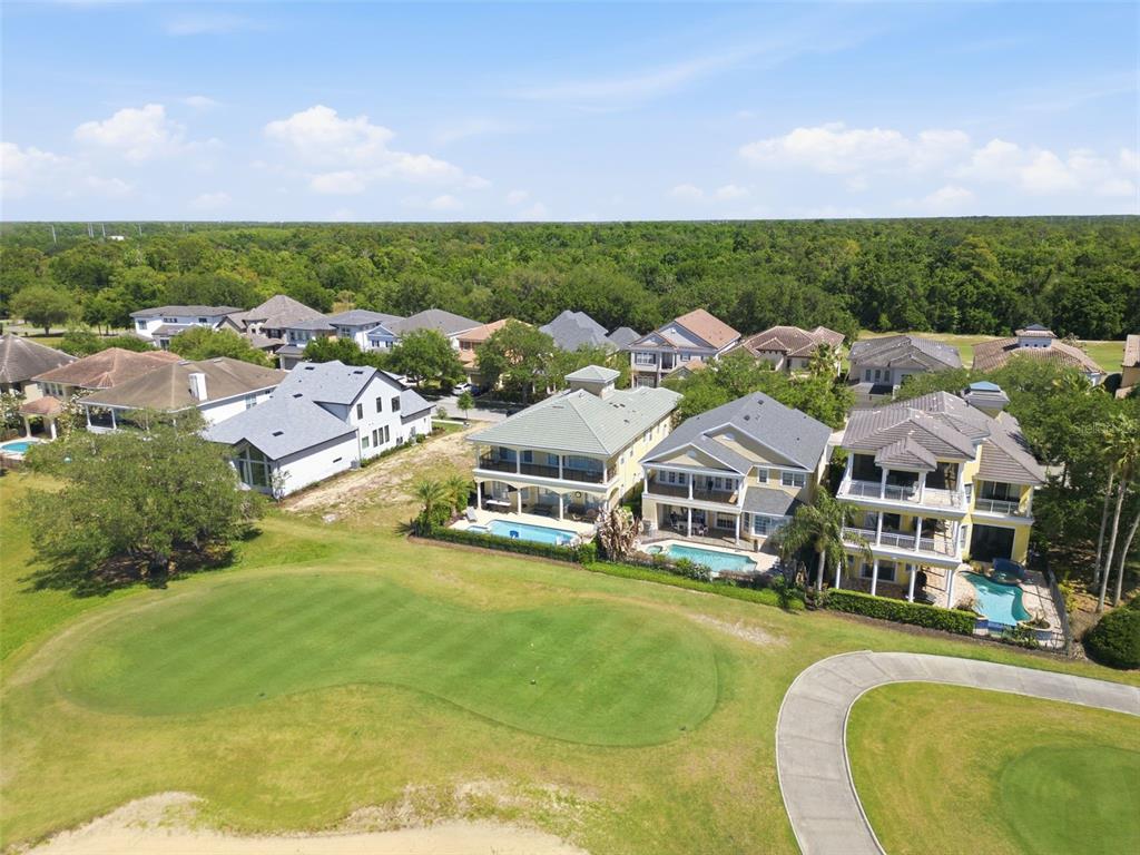 An aerial view shows several houses with swimming pools bordering a golf course green — 7390 GATHERING COURT, KISSIMMEE, FL