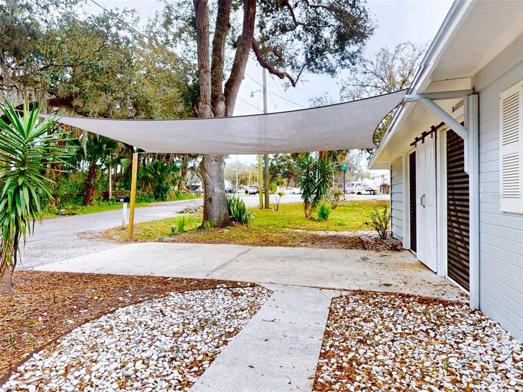 A concrete patio area features a white shade sail attached to the side of a house — 104 FRAN DRIVE, NEW SMYRNA BEACH, FL