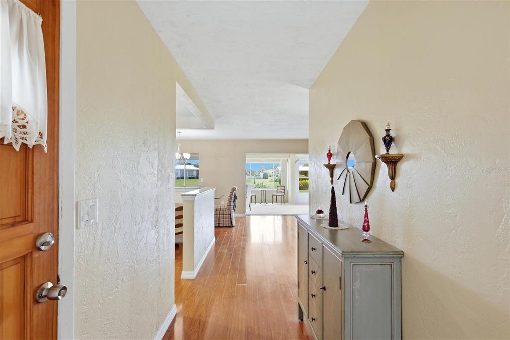 A view from an entryway looking into a living area with hardwood floors and furniture — 3262 BROCKTON LANE UNIT 608, SARASOTA, FL