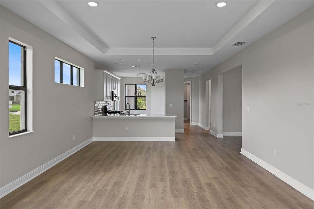 A bright, open-concept kitchen and living area featuring light wood floors and a tray ceiling — 18340 ROCKPORT PLACE, LAKEWOOD RANCH, FL