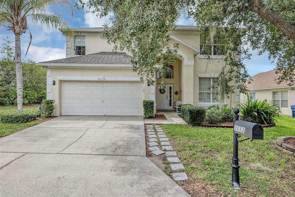 A two-story suburban house with a beige stucco exterior, a two-car garage, and a driveway — 3112 ANTIQUA WAY, HAINES CITY, FL