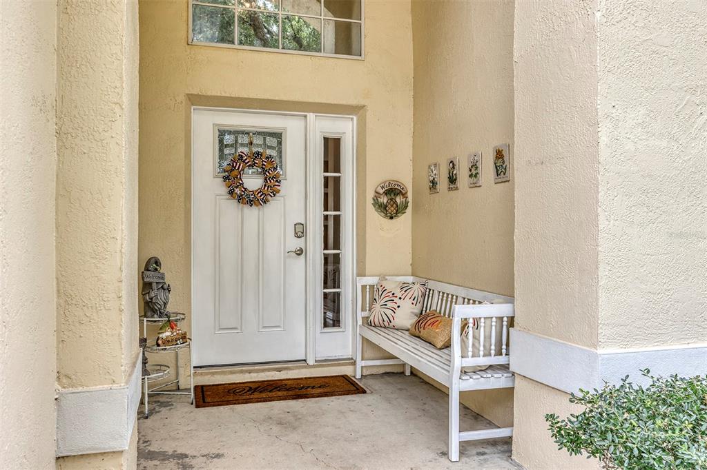A front porch features a white door with a wreath, a bench, and decorative wall tiles — 3112 ANTIQUA WAY, HAINES CITY, FL