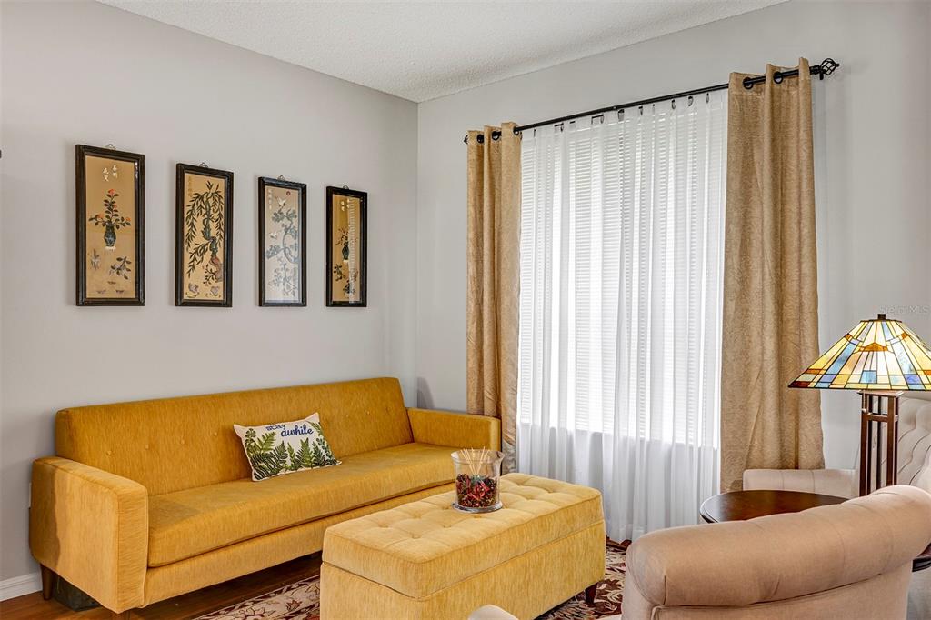 A living room features a yellow sofa, matching ottoman, four wall hangings, and a stained-glass lamp — 3112 ANTIQUA WAY, HAINES CITY, FL