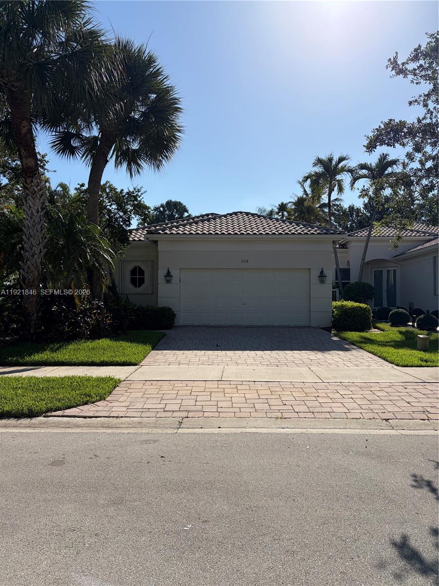 A single-story house with a beige exterior, a two-car garage, and palm trees — 2518 Bay Pointe Ct, Weston FL 33327, WESTON, FL