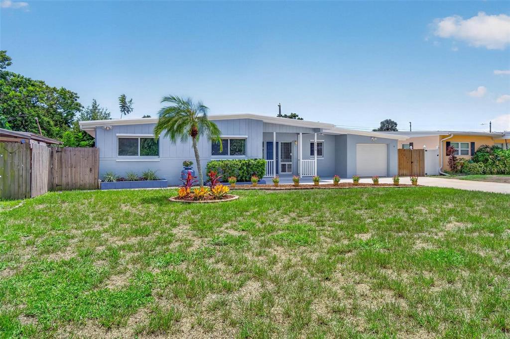 A single-story light blue house with a front lawn, palm tree, and attached garage — 5520 8TH AVENUE N, ST PETERSBURG, FL