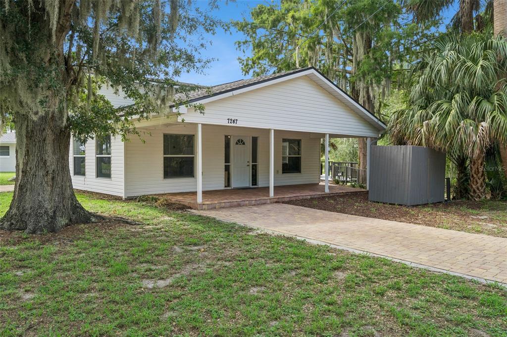 A single-story white house with a covered front porch and a paved driveway — 7247 TREASURE ISLAND ROAD, LEESBURG, FL