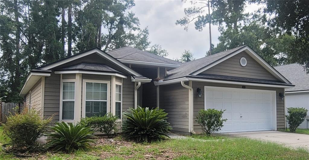 A single-story house with gray horizontal siding, a white garage door, and a bay window — 4931 NW 81ST AVENUE, GAINESVILLE, FL