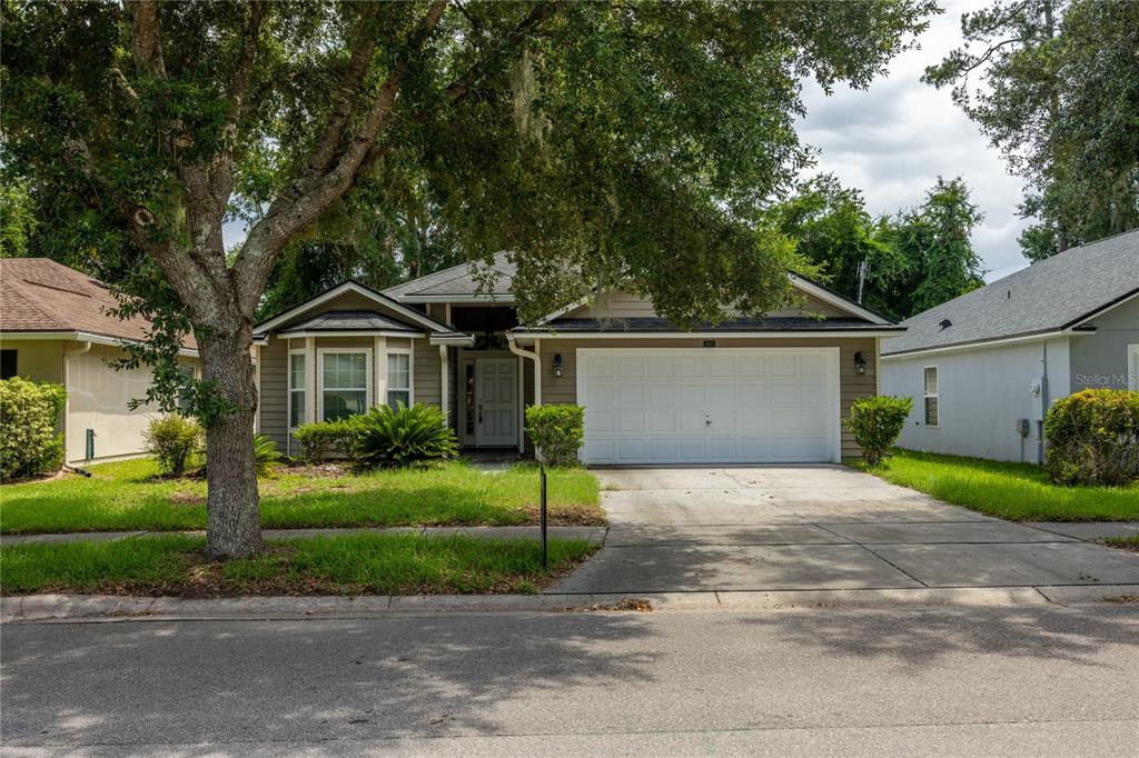 A single-story house with a two-car garage and a large tree in the front yard — 4931 NW 81ST AVENUE, GAINESVILLE, FL