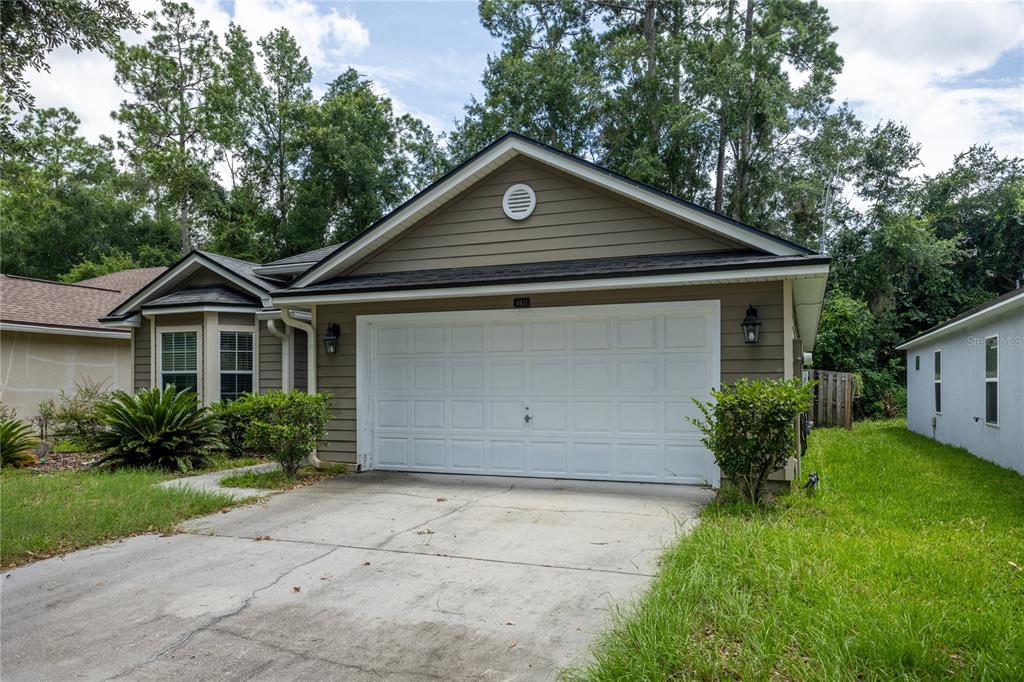 A single-story house with a tan exterior, a white garage door, and a concrete driveway — 4931 NW 81ST AVENUE, GAINESVILLE, FL
