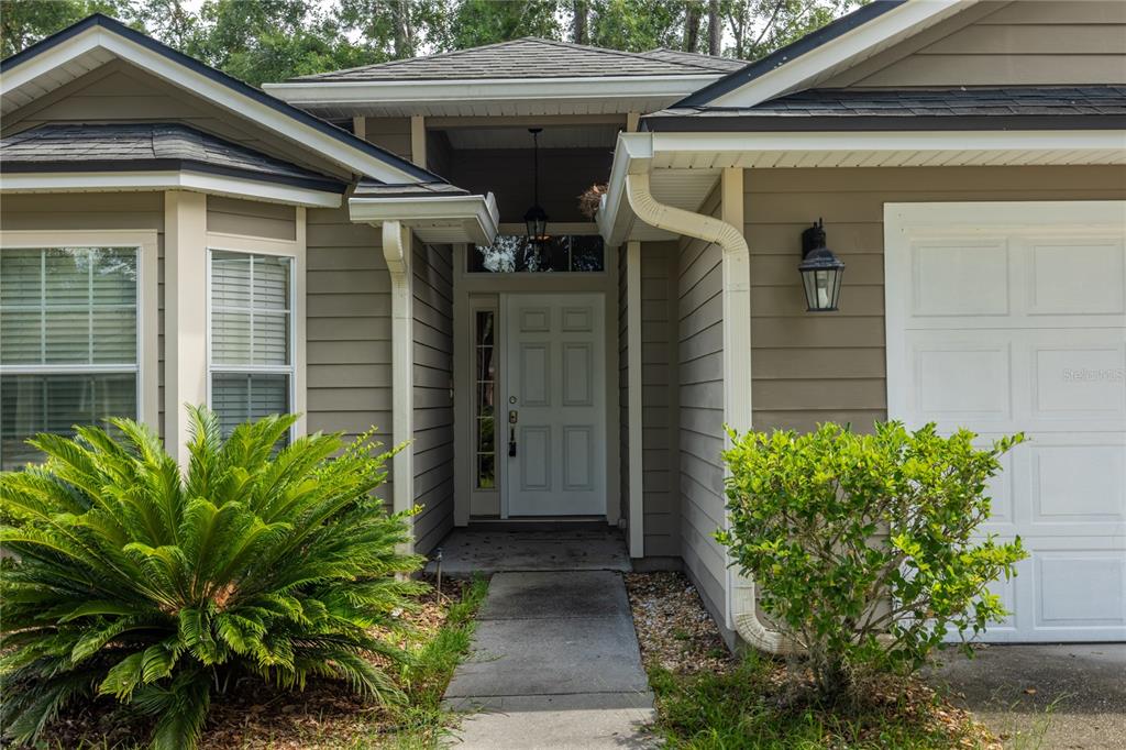 The exterior of a house features a white front door, a walkway, and landscaping — 4931 NW 81ST AVENUE, GAINESVILLE, FL