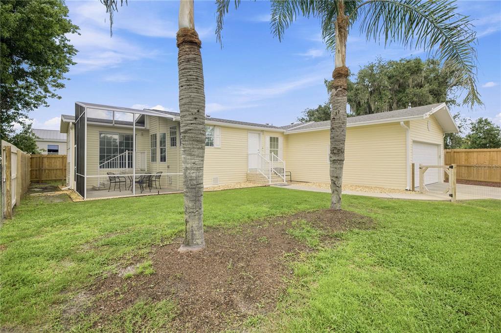 A yellow house with a screened-in porch, a garage, and two palm trees in the yard — 5230 LEXINGTON CIRCLE, WILDWOOD, FL