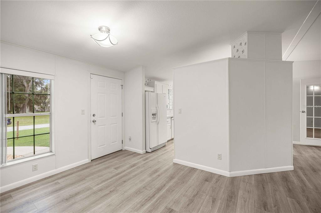 A bright room with light wood-look flooring, a white front door, and a central partition — 5230 LEXINGTON CIRCLE, WILDWOOD, FL