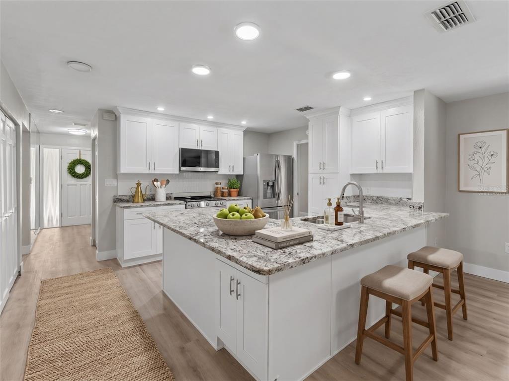 A bright kitchen features white cabinets, granite countertops, a central island, and light wood flooring — 162 W MASSACHUSETTS STREET, HERNANDO, FL