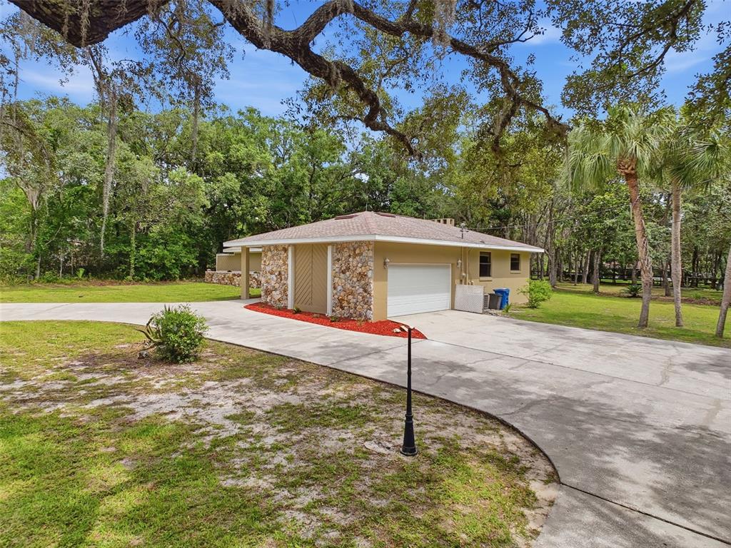 A single-story house with a stone-accented exterior and a white garage door sits on grass — 162 W MASSACHUSETTS STREET, HERNANDO, FL