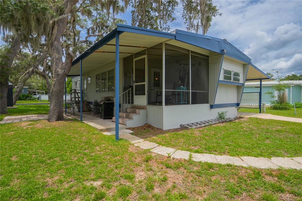 A mobile home with a screened-in porch, metal roof, and a stone walkway on grass — 3896 PICCIOLA ROAD UNIT 534, FRUITLAND PARK, FL