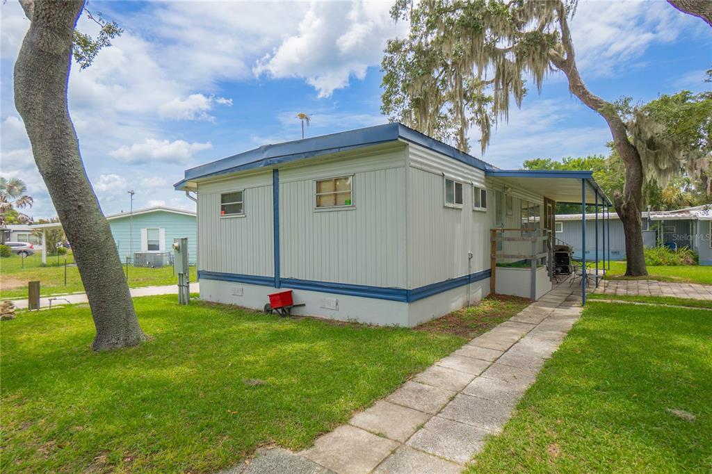 A light-colored mobile home with a metal roof and a concrete walkway in a yard — 3896 PICCIOLA ROAD UNIT 534, FRUITLAND PARK, FL