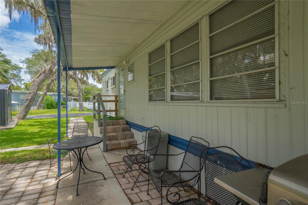 A patio with metal furniture sits under a covered porch beside a mobile home — 3896 PICCIOLA ROAD UNIT 534, FRUITLAND PARK, FL
