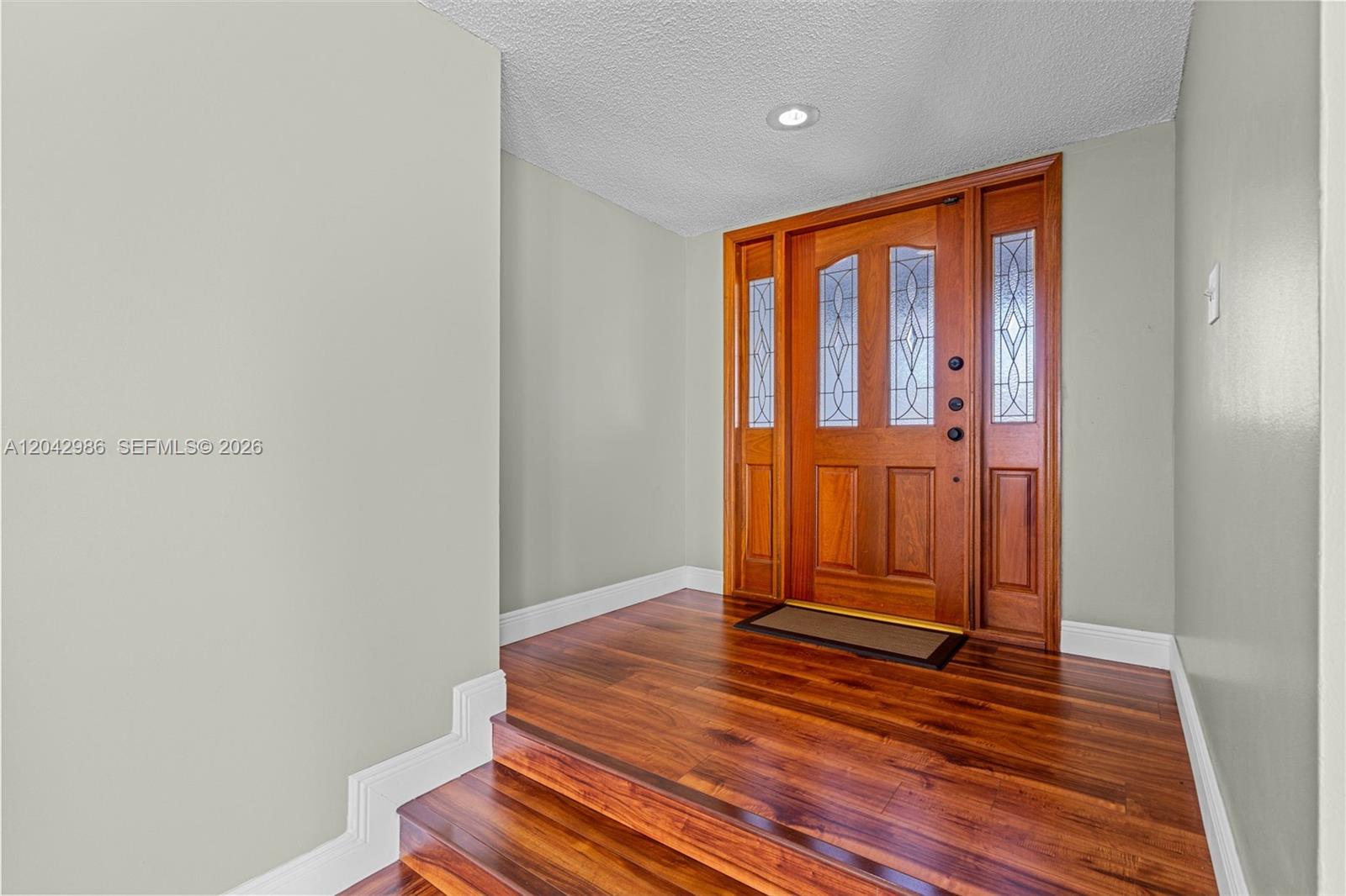 An entryway features a wooden front door with glass panels and hardwood flooring — 12535 SW 95th Ter, Miami FL 33186, MIAMI, FL