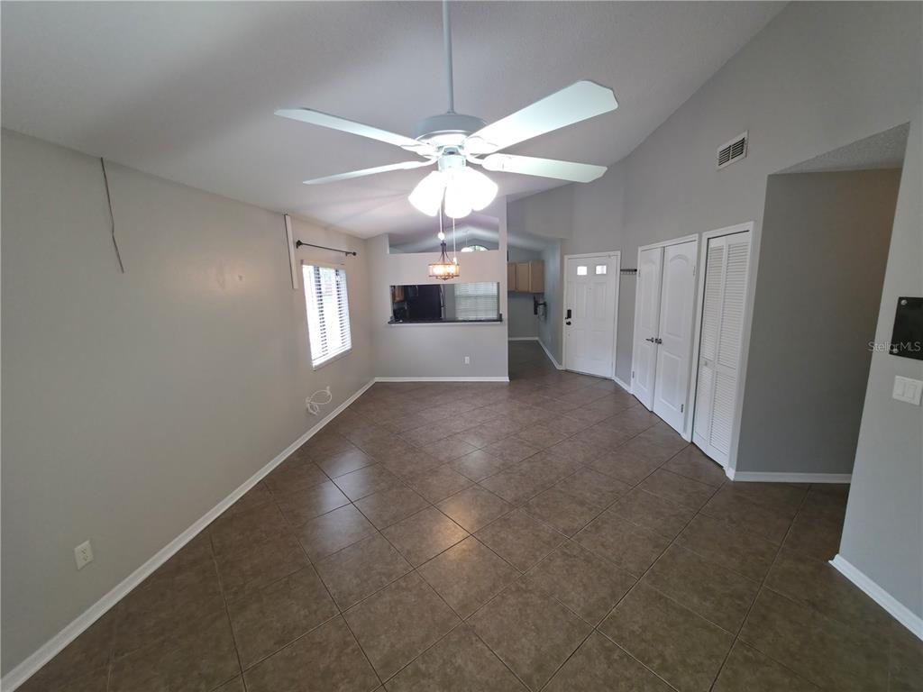 A room with light gray walls, brown tile flooring, a ceiling fan, and white doors — 2201 GRASMERE DRIVE, APOPKA, FL