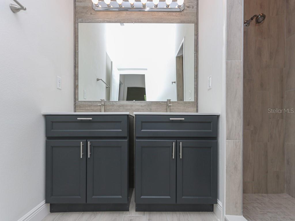 A bathroom features a double vanity with dark gray cabinets and a wood-look tile backsplash — 2831 W LIVINGSTON STREET, ORLANDO, FL