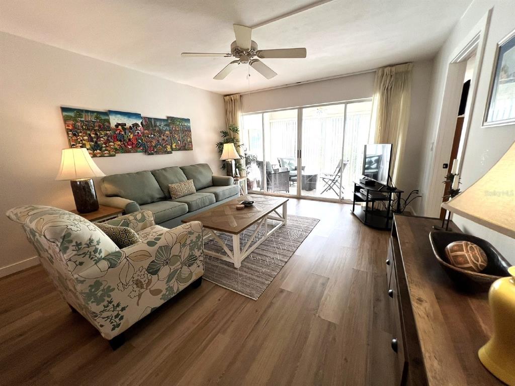 A living room features a sofa, floral armchair, coffee table, and sliding glass doors to a patio — 5205 WEDGEWOOD LN UNIT 15, SARASOTA, FL