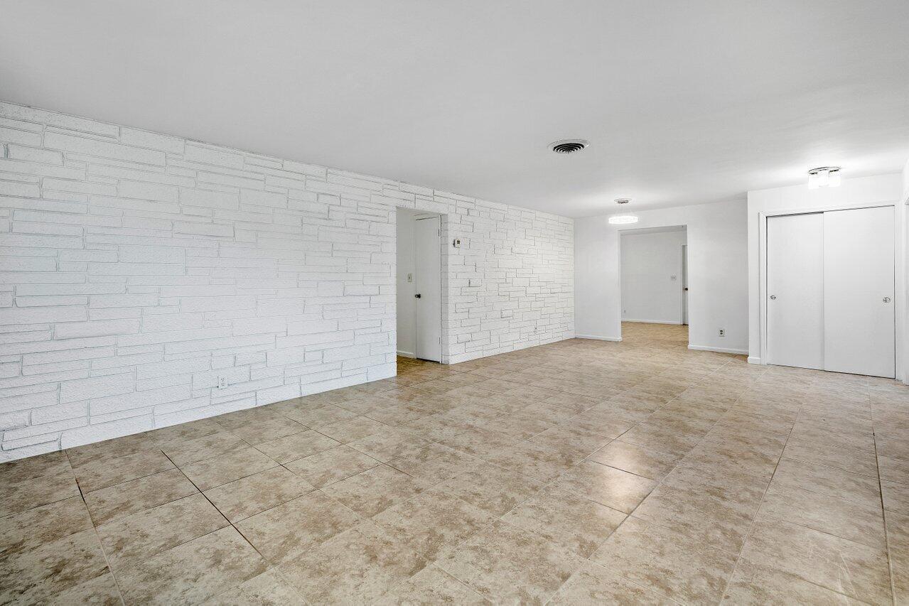 A room with white stone accent walls, beige tile flooring, and white closet doors — 617 SE 8th Avenue, Deerfield Beach FL 33441, DEERFIELD BEACH, FL