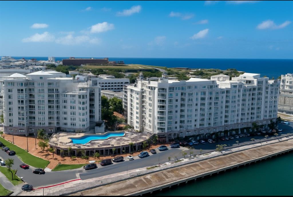 An aerial view of a large white apartment complex with a pool overlooking the ocean — 100 DEL MUELLE UNIT 1301, SAN JUAN, PR
