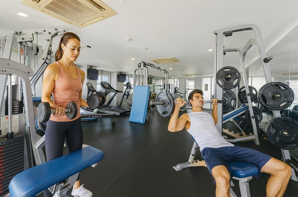 A gym features a woman lifting dumbbells and a man performing a barbell bench press — 100 DEL MUELLE UNIT 1301, SAN JUAN, PR