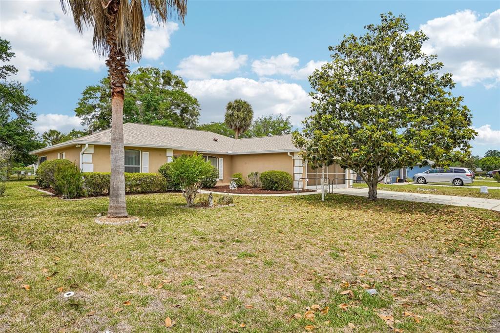 A single-story tan house with a palm tree and a large tree in the yard — 86 BAHIA TRACE TRAIL, OCALA, FL