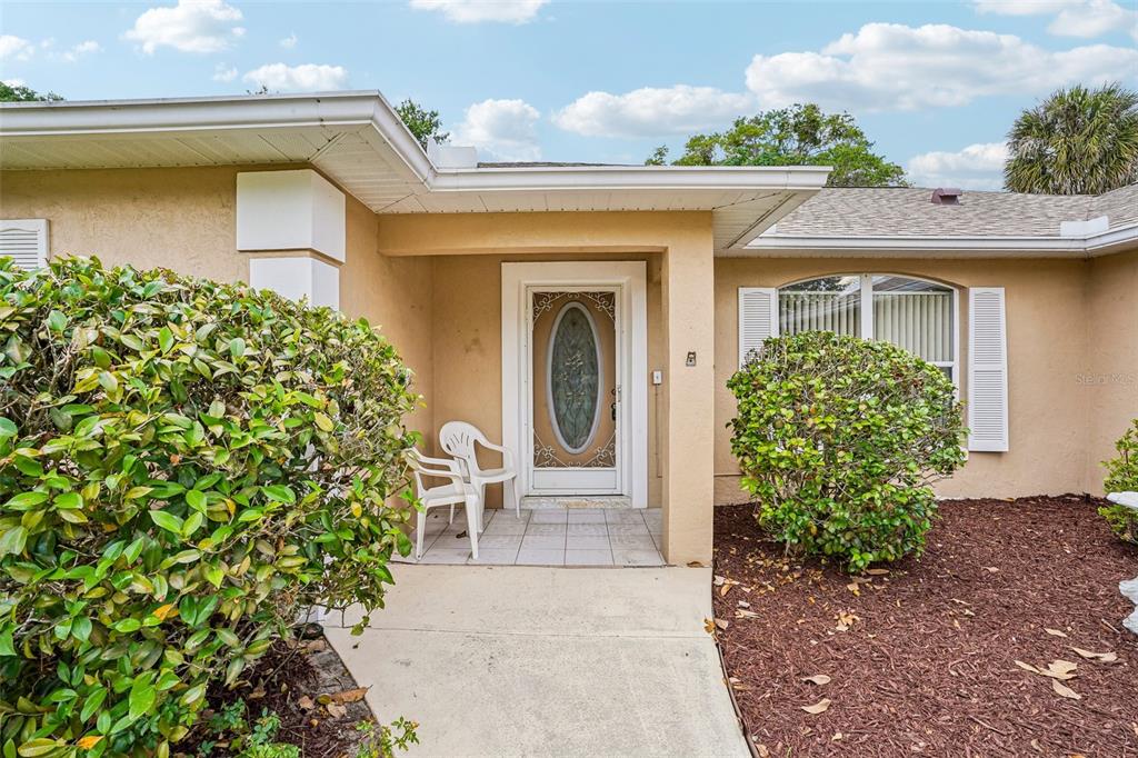 The exterior of a beige house features a covered entryway with a glass-paneled front door — 86 BAHIA TRACE TRAIL, OCALA, FL
