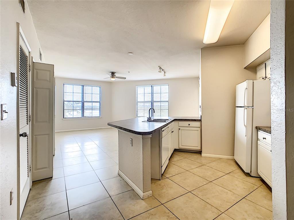 A kitchen with white cabinets and a tile floor opens into a living area — 911 N ORANGE AVENUE UNIT 441, ORLANDO, FL