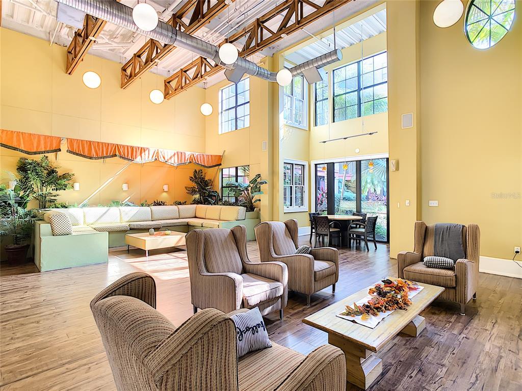 A spacious, high-ceilinged lounge features a large sectional sofa, armchairs, and wood-look flooring — 911 N ORANGE AVENUE UNIT 441, ORLANDO, FL