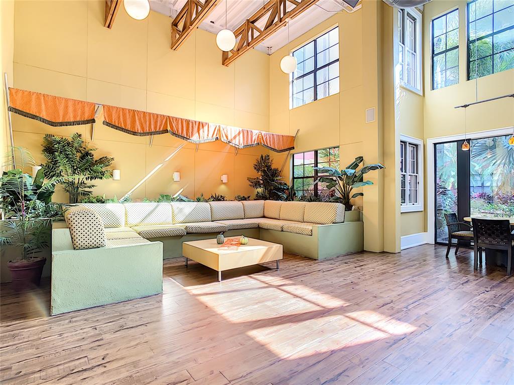 A spacious living room features a large sectional sofa, high ceilings, and wood-look flooring — 911 N ORANGE AVENUE UNIT 441, ORLANDO, FL