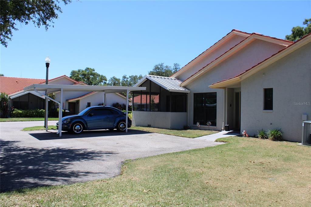 A single-story house with a carport, a screened-in porch, and a blue car parked outside — 2288 CITRUS COURT, CLEARWATER, FL