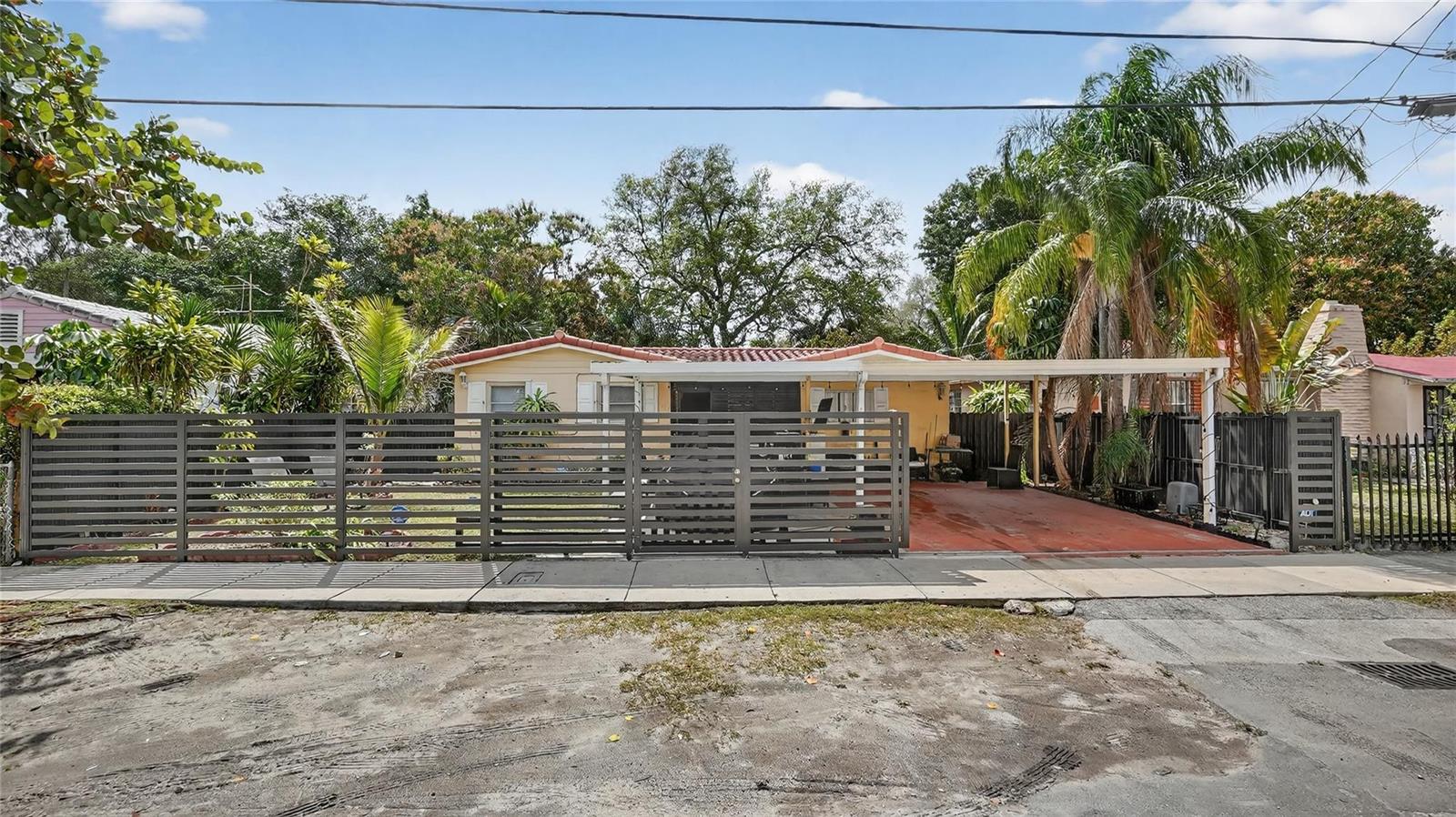 A single-story house with a carport is enclosed by a modern horizontal slat fence — 154 NW 67th Street, Miami FL 33150, MIAMI, FL