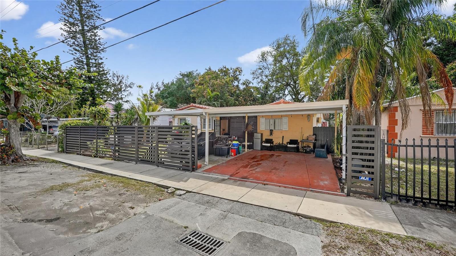 A house exterior features a covered carport, a gated driveway, and a fenced front yard — 154 NW 67th Street, Miami FL 33150, MIAMI, FL