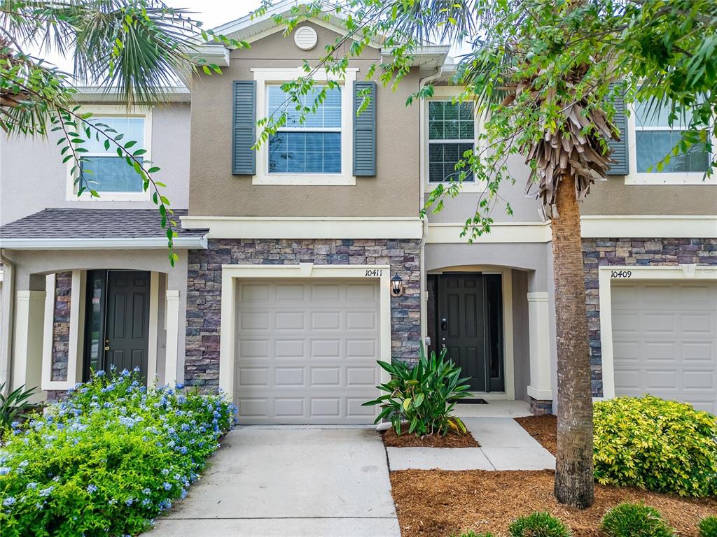 A two-story townhouse exterior features a stone facade, a garage, and a front entrance — 10411 RED CARPET COURT, RIVERVIEW, FL