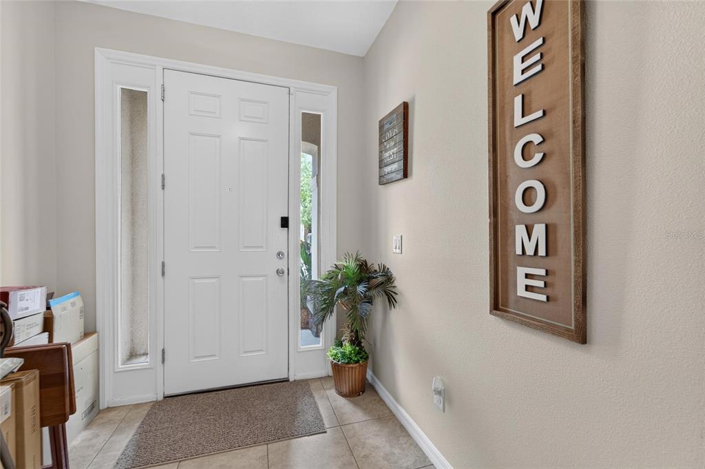 A tiled entryway features a white front door with sidelights and a large welcome sign — 10411 RED CARPET COURT, RIVERVIEW, FL