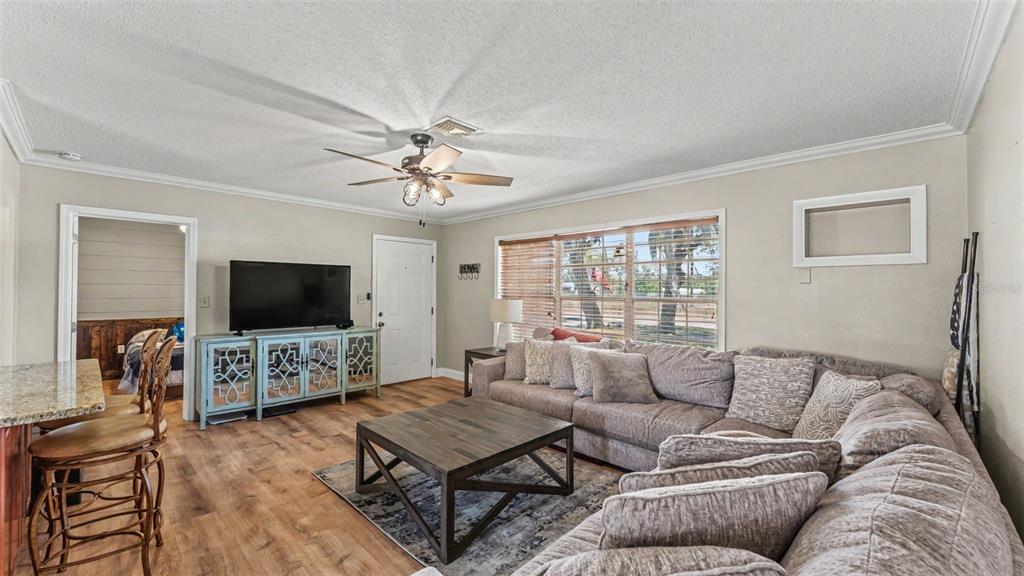 A living room features a large sectional sofa, a wooden coffee table, and a television console — 1422 NANCESOWEE AVENUE, SEBRING, FL