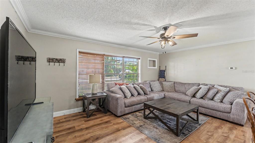 A living room features a large sectional sofa, a coffee table, and wood-look flooring — 1422 NANCESOWEE AVENUE, SEBRING, FL