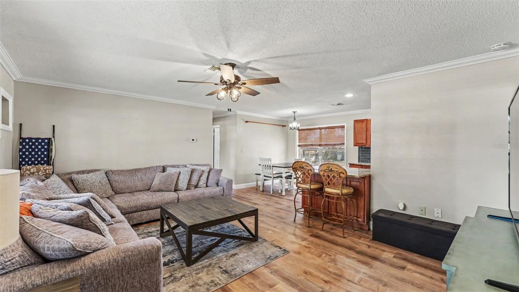 A living room with a sectional sofa, coffee table, and an adjacent kitchen breakfast bar — 1422 NANCESOWEE AVENUE, SEBRING, FL