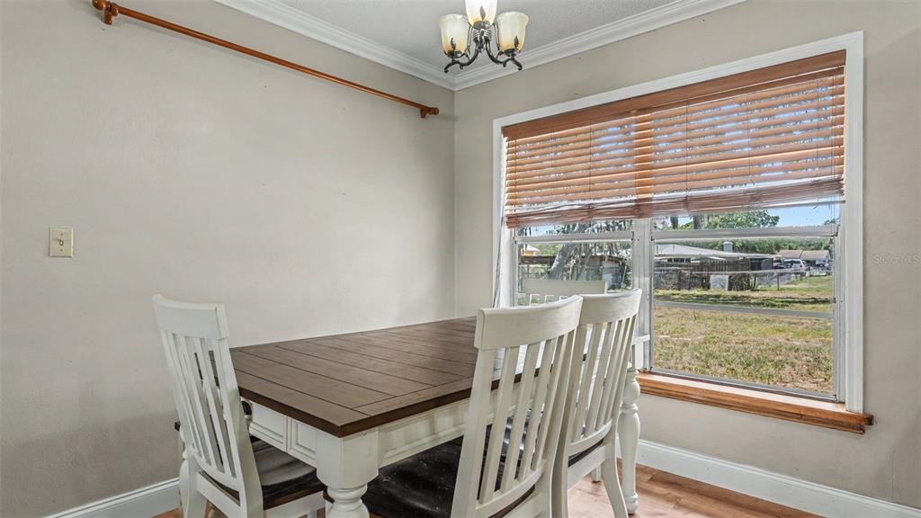 A dining room features a wooden table, white chairs, and a window with wood blinds — 1422 NANCESOWEE AVENUE, SEBRING, FL