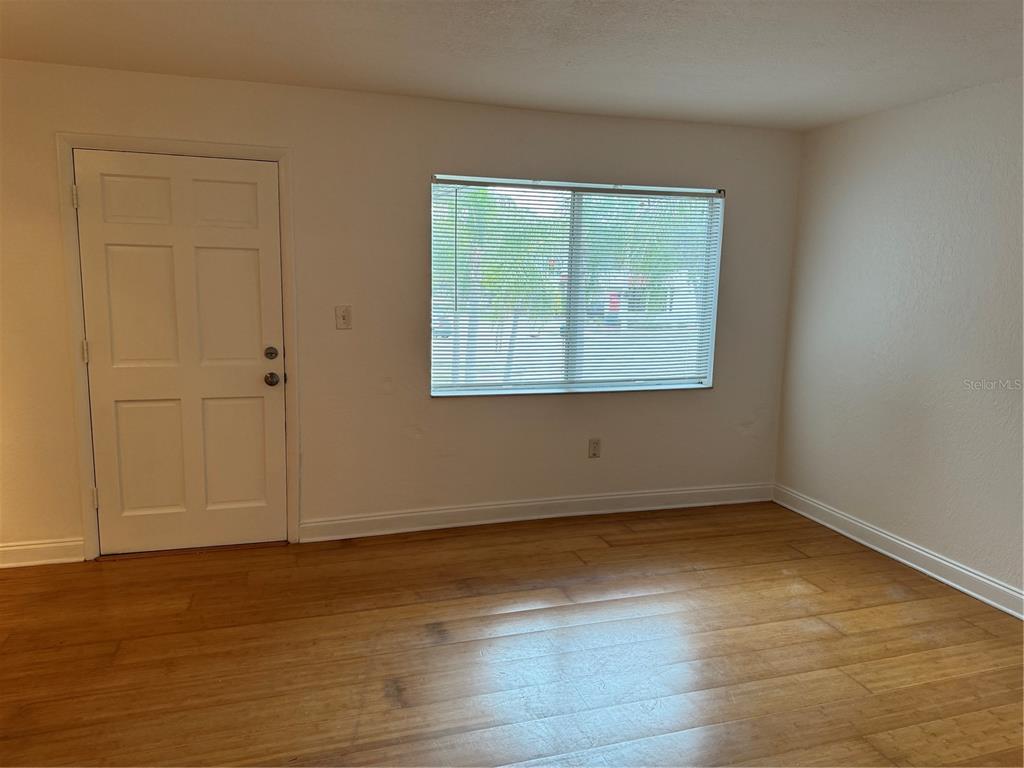 An empty room features light wood flooring, a white door, and a window with blinds — 3914 W NEPTUNE STREET UNIT 29, TAMPA, FL